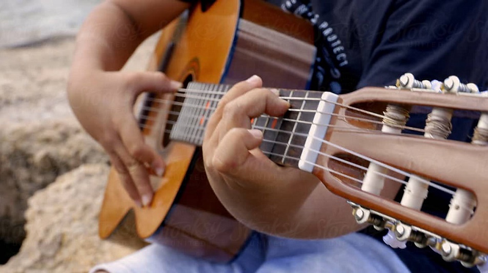 close up of a boys hand playing the guitar